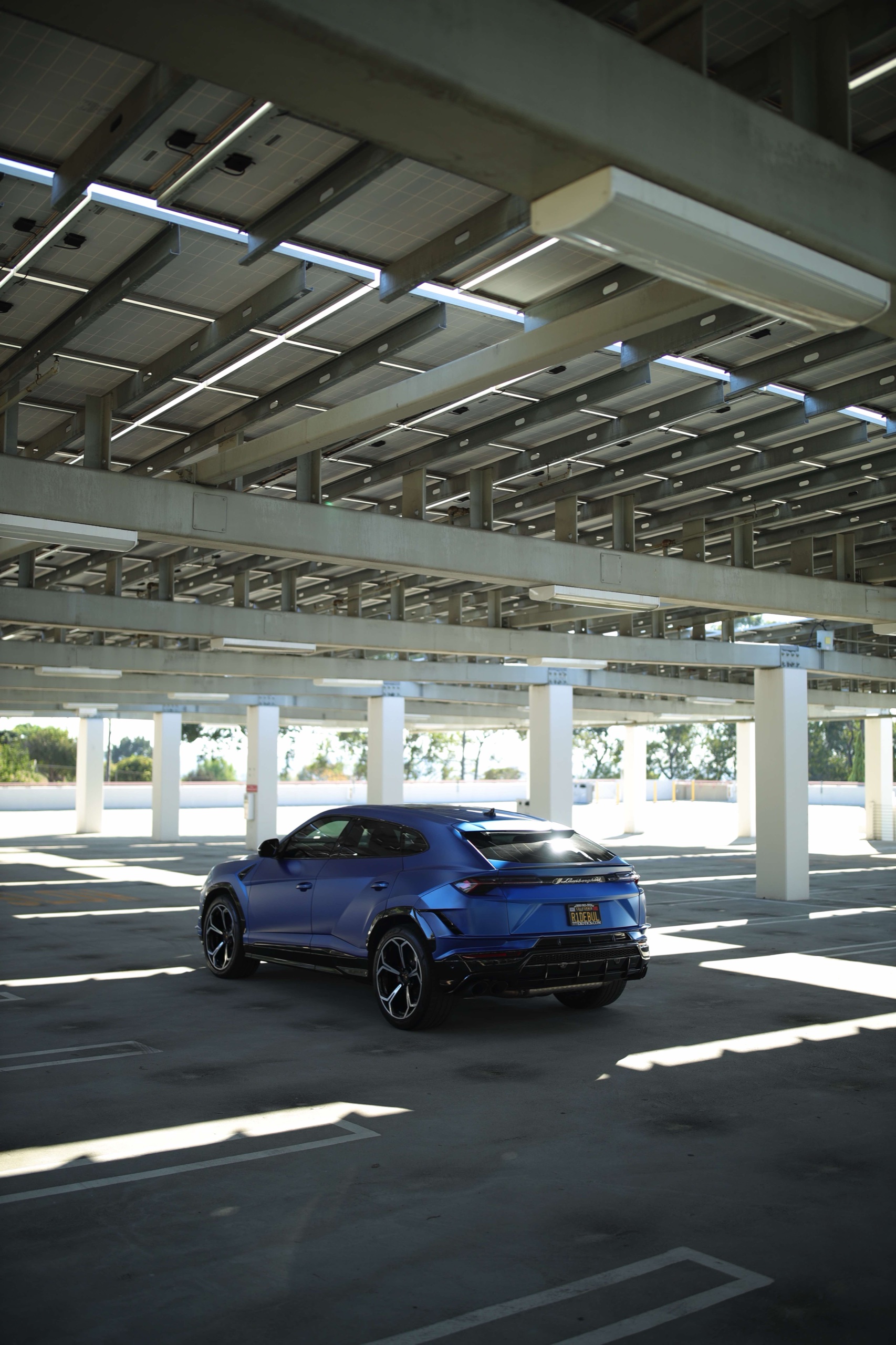 Wide rear view of the Frozen Blue Lamborghini Urus S under a canopy